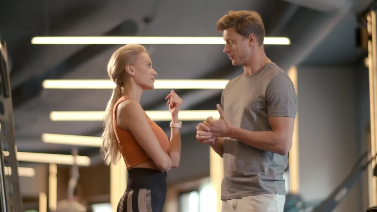 Smiling fitness couple talking at gym Fit man and woman speaking in sport club