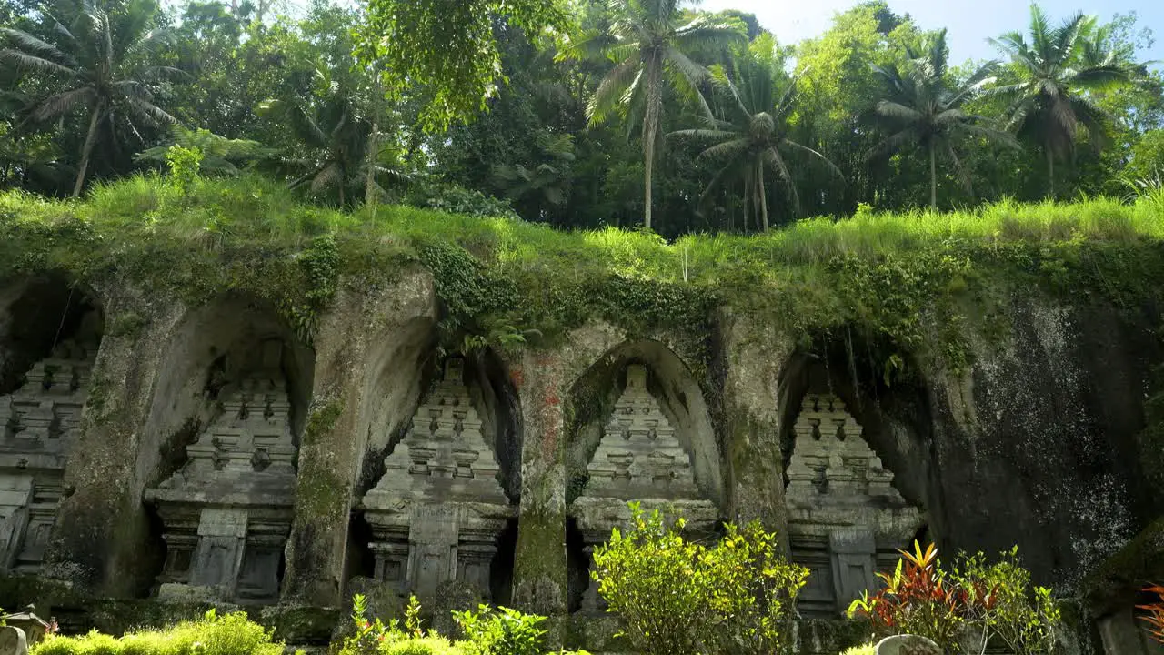 Tilt up shot of historical ruins of a temple on bali indonesia with a fountain and view of the dense jungle