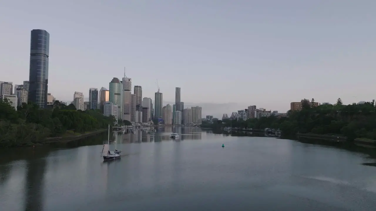 Cinematic Drone flying low over River towards Brisbane City at Sunrise