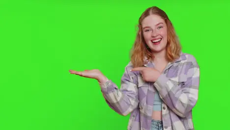 Young woman showing thumbs up and pointing at left on blank space place for your advertisement logo