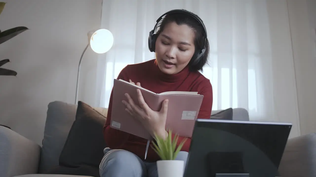 Freelance woman redshirt using tablet with headphone for meeting online at home