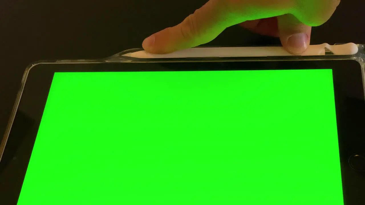 Man puts away pen after use on ipad with green screen top view