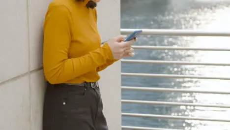 Pull Focus Shot of Young Woman Texting On Her Mobile Phone