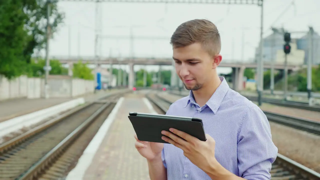 Young Man Uses A Tablet At A Train Station