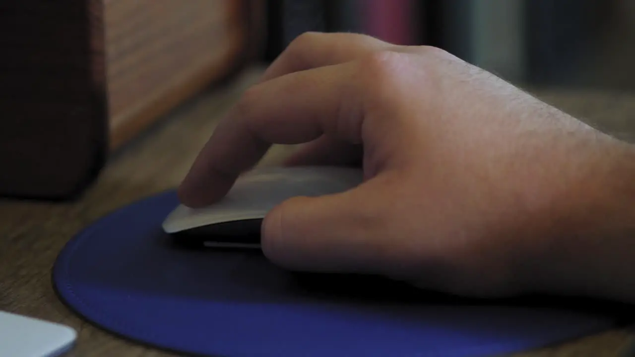 Man uses computer mouse with blue mouse pad close up