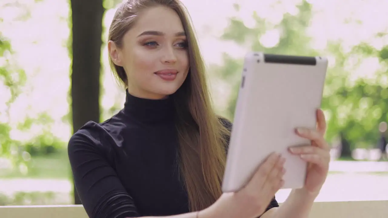 Young smiling woman using tablet for online conversation