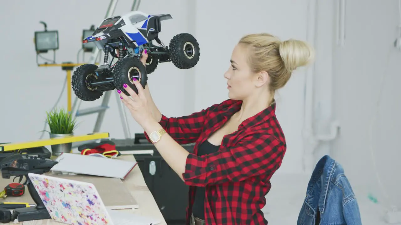 Woman examining radio controlled car in workshop