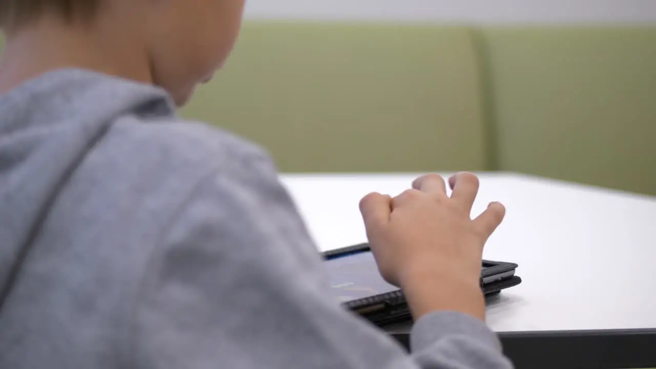 Close up behind blond boy reading on tablet Static