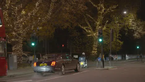 Traffic At Traffic Lights In London With Trees Decorated With Lights For Christmas