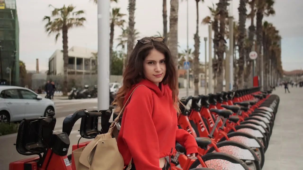 Young girl looking at the camera in a bycicle for rent parking