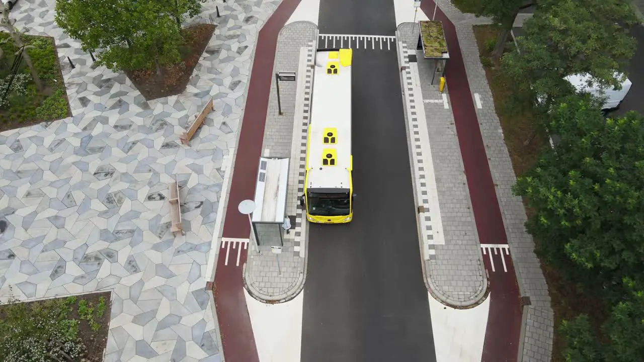 Birds eye view of public transportation bus arriving at bus stop in clean city center of a ecological neighborhood