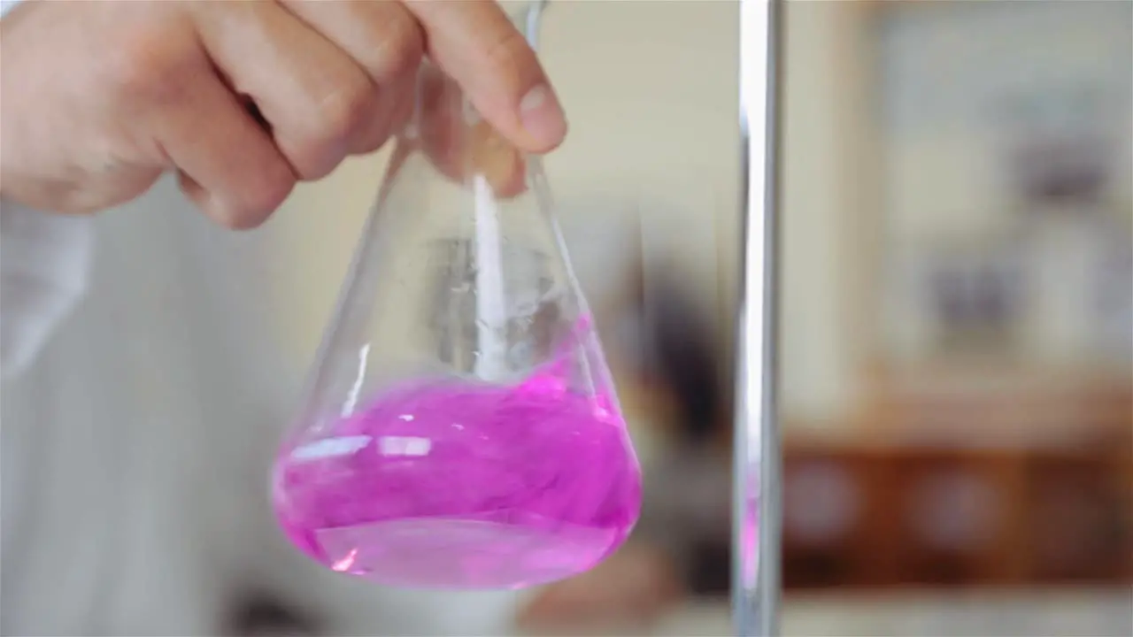 Scientist Mixing Titrant And Analyte In An Erlenmeyer Flask By Shaking In An Orbital Motion Titration Procedure In The Lab close up