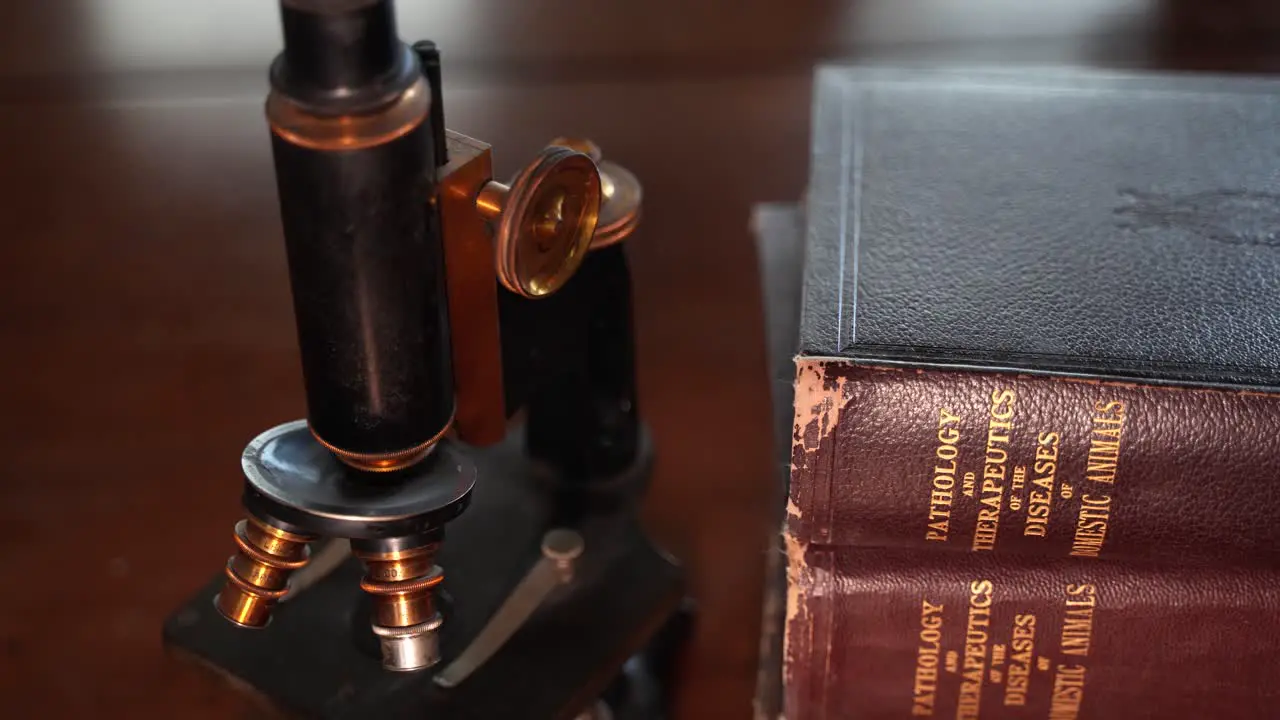 An antique microscope and old medical pathology books for domestic animals doctor veterinarian's office desk