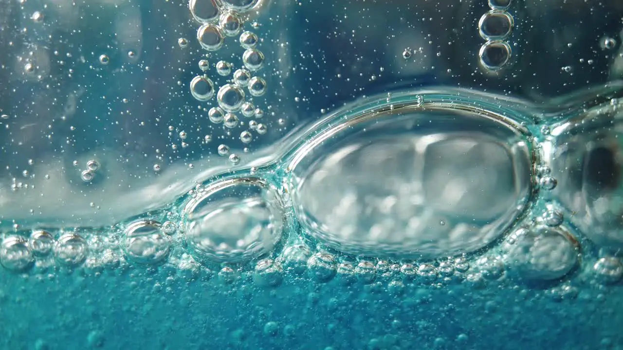 Large and small bubbles fall slowly in blue liquid fluid background