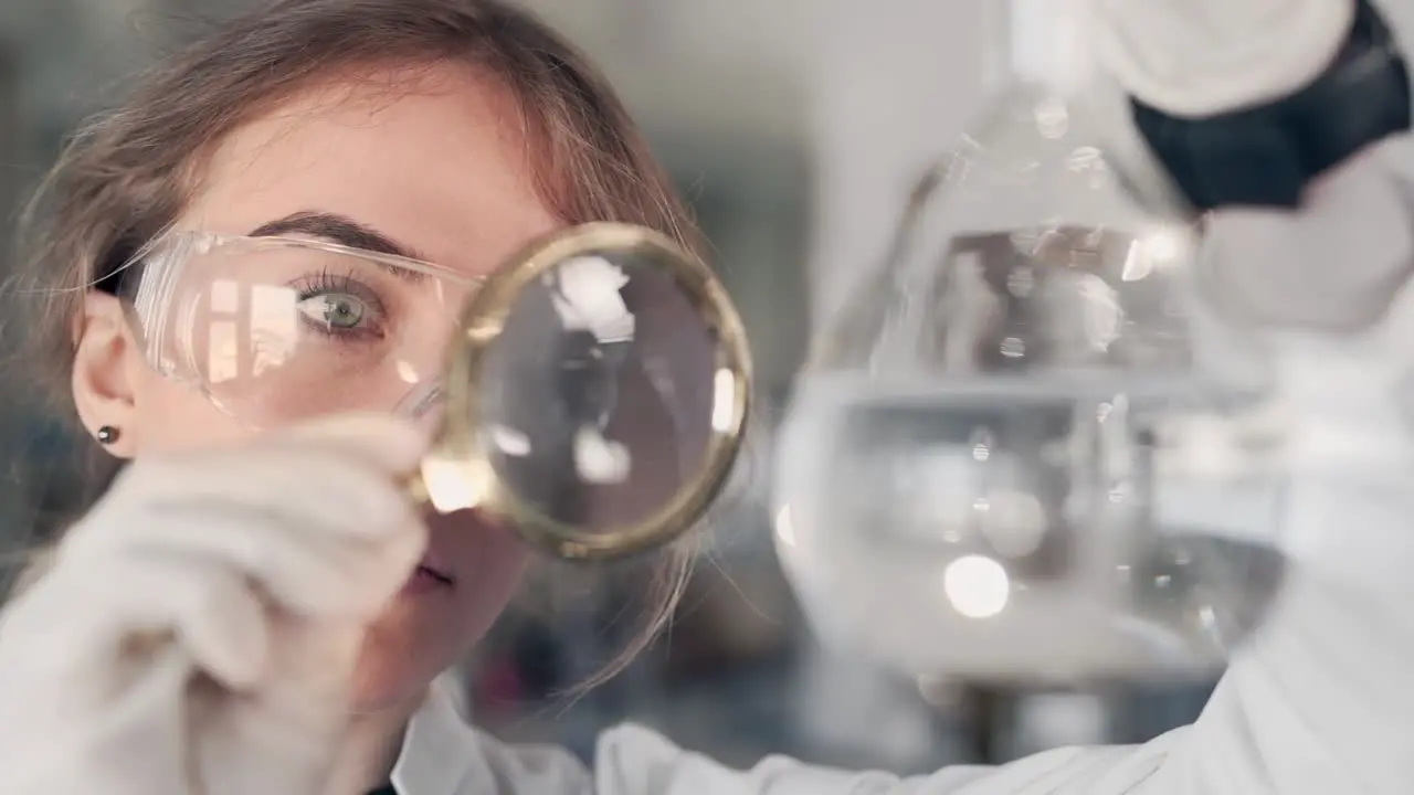 female scientist examines a liquid in a tube with a magnifying glass