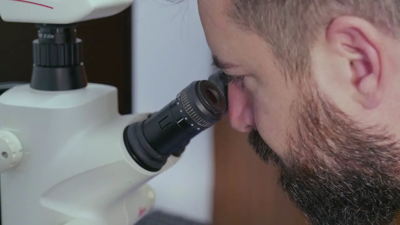 Close-up of a man looking into a microscope