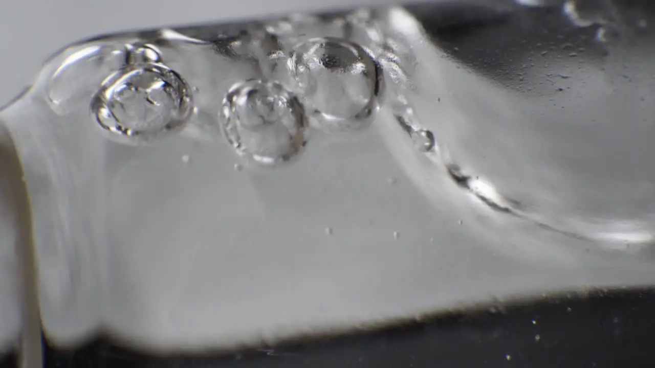 Macro shot of clear liquid with few bubbles on the surface slowly moving in reagent tube