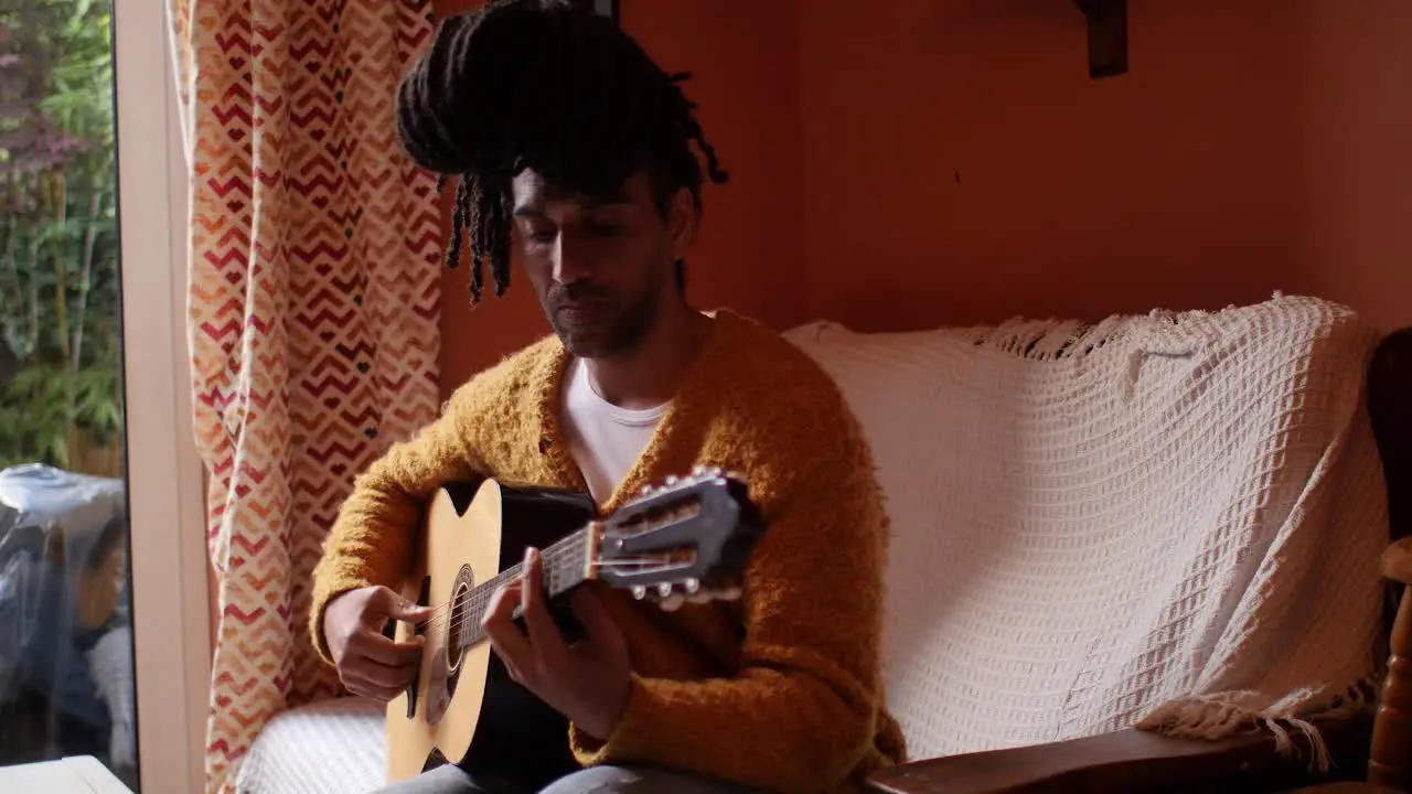 Stylish afro model playing guitar in the living room