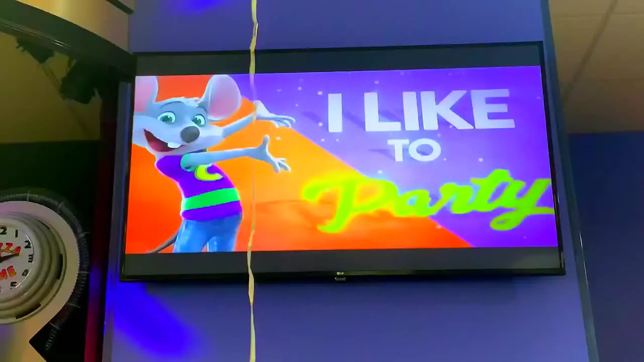 Let's party balloon bouncing up and down in front of a colorful screen that says "I like to party with Chuck E