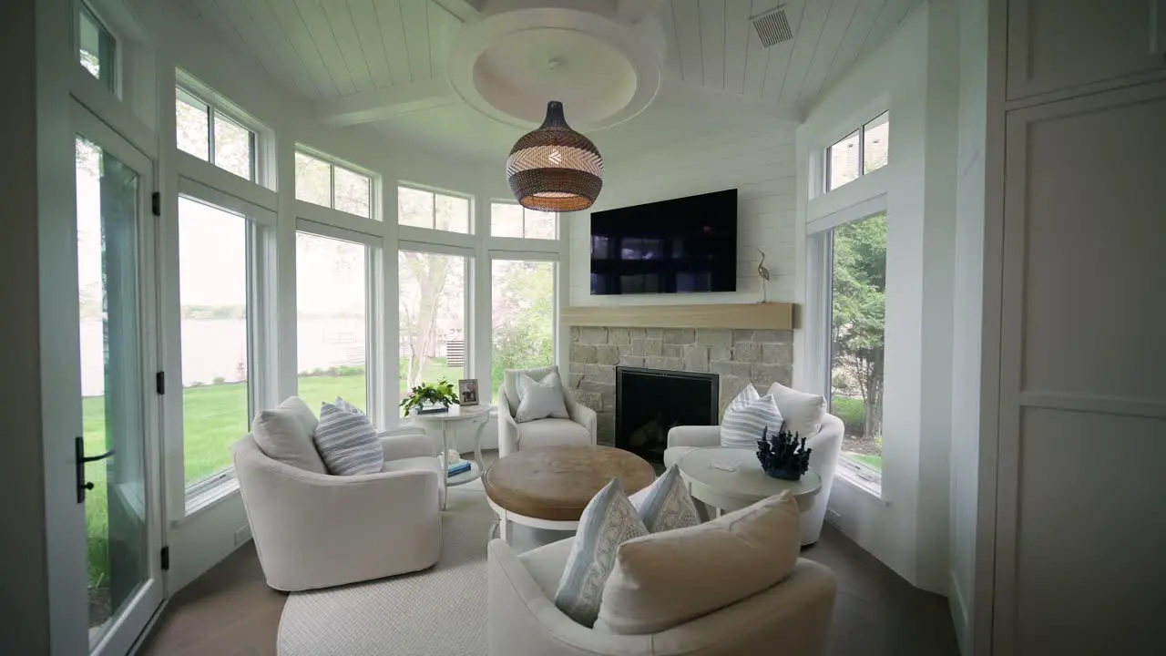 Cozy circular hearth room with white chairs natural light windows and television