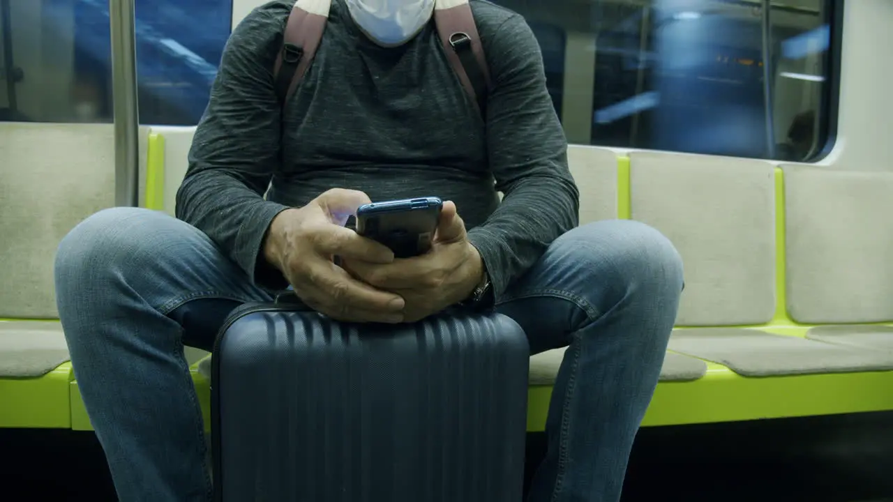 Man traveler with suitcase using phone in subway train