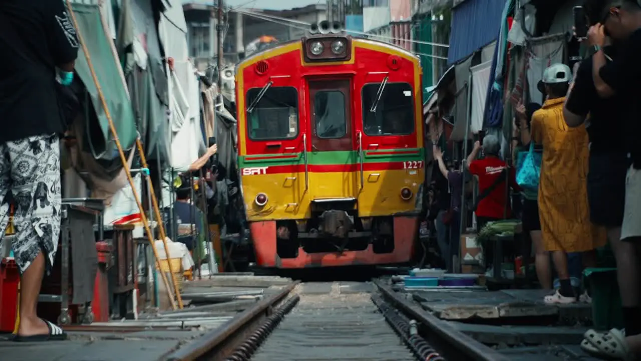 Slow motion train travelling on railway through local village in Asia