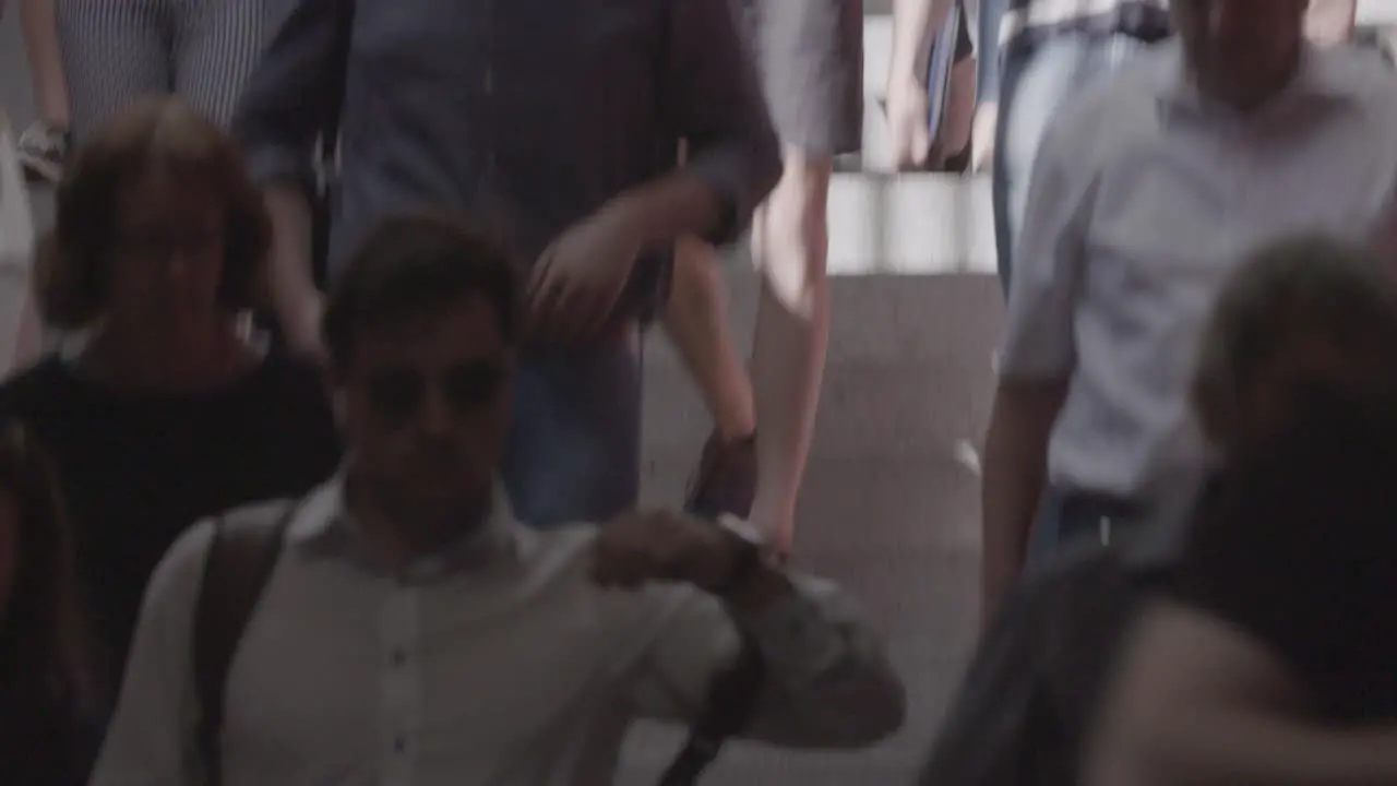 Slowmotion shot of a crowd of people transitioning from the sun to the shadow as they come down a subway tunnel in Munich Germany