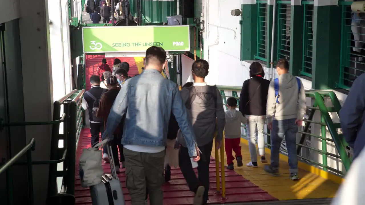 People leaving the ferry on a ramp in Hong Kong