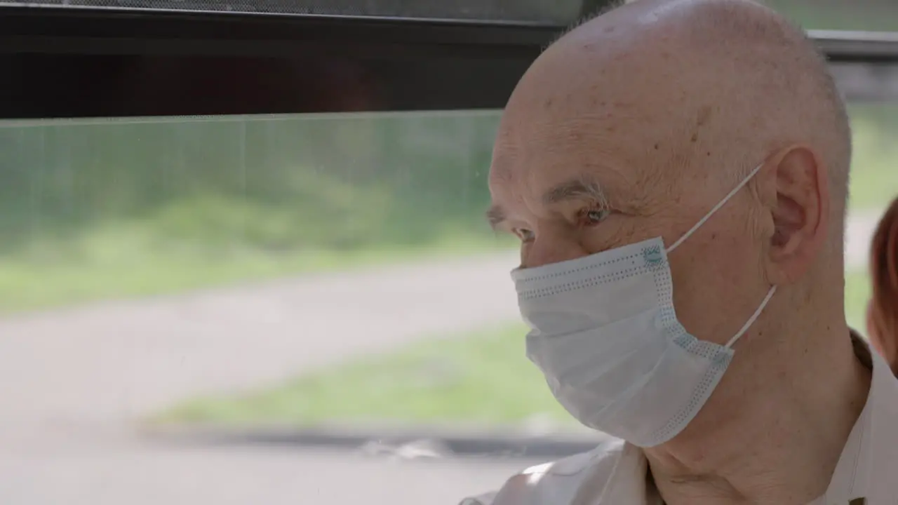 Senior man in medical mask is on a bus