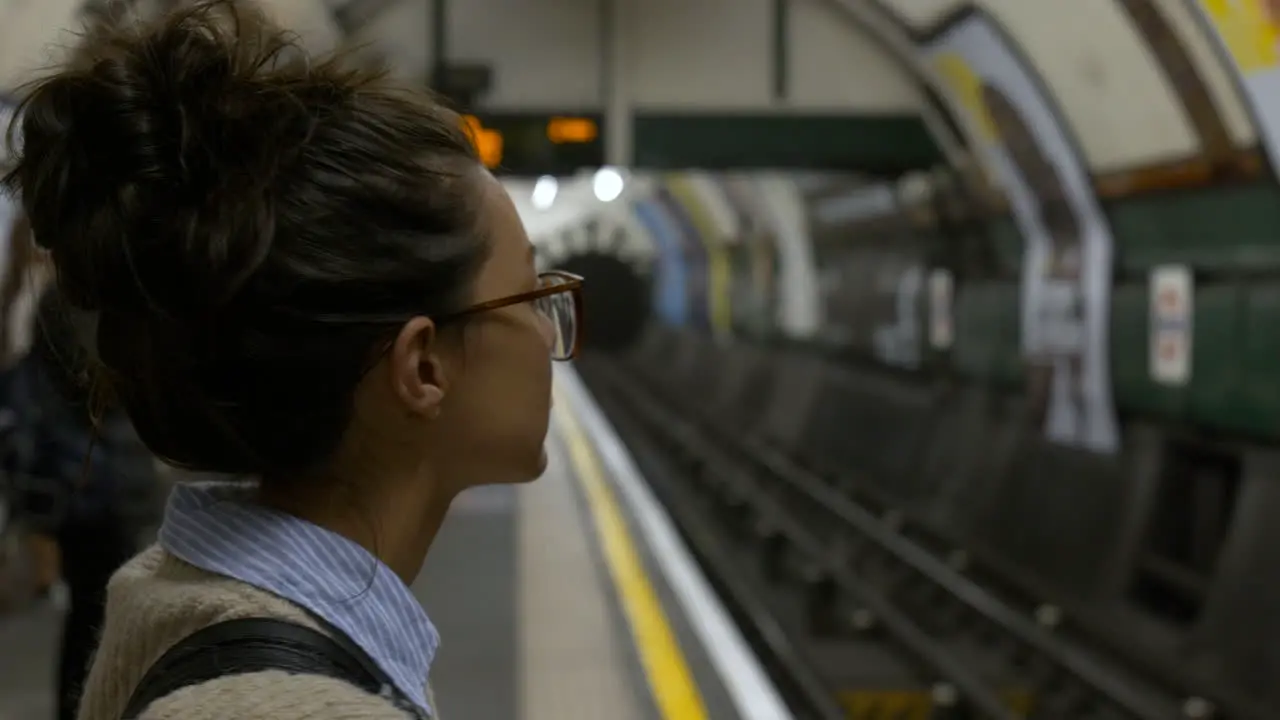 Woman stood on underground platform waiting for tube train London