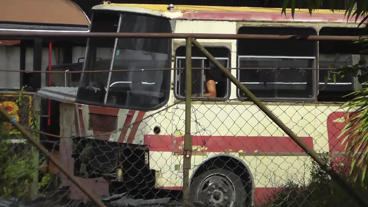 A Cuban bus driver is reversing a typical old bus that looks rusty and broken but is still getting used as a transportation vehicle