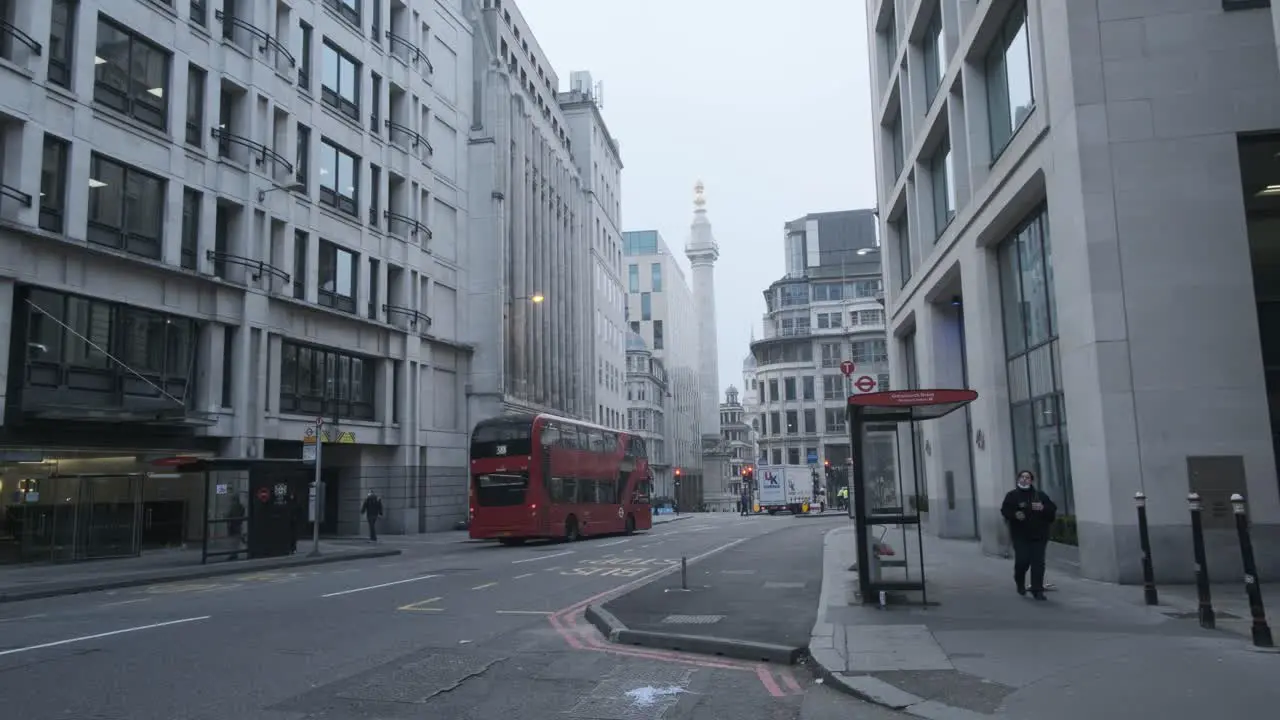 London double decker buses driving down gracechurch street monument on foggy winter morning