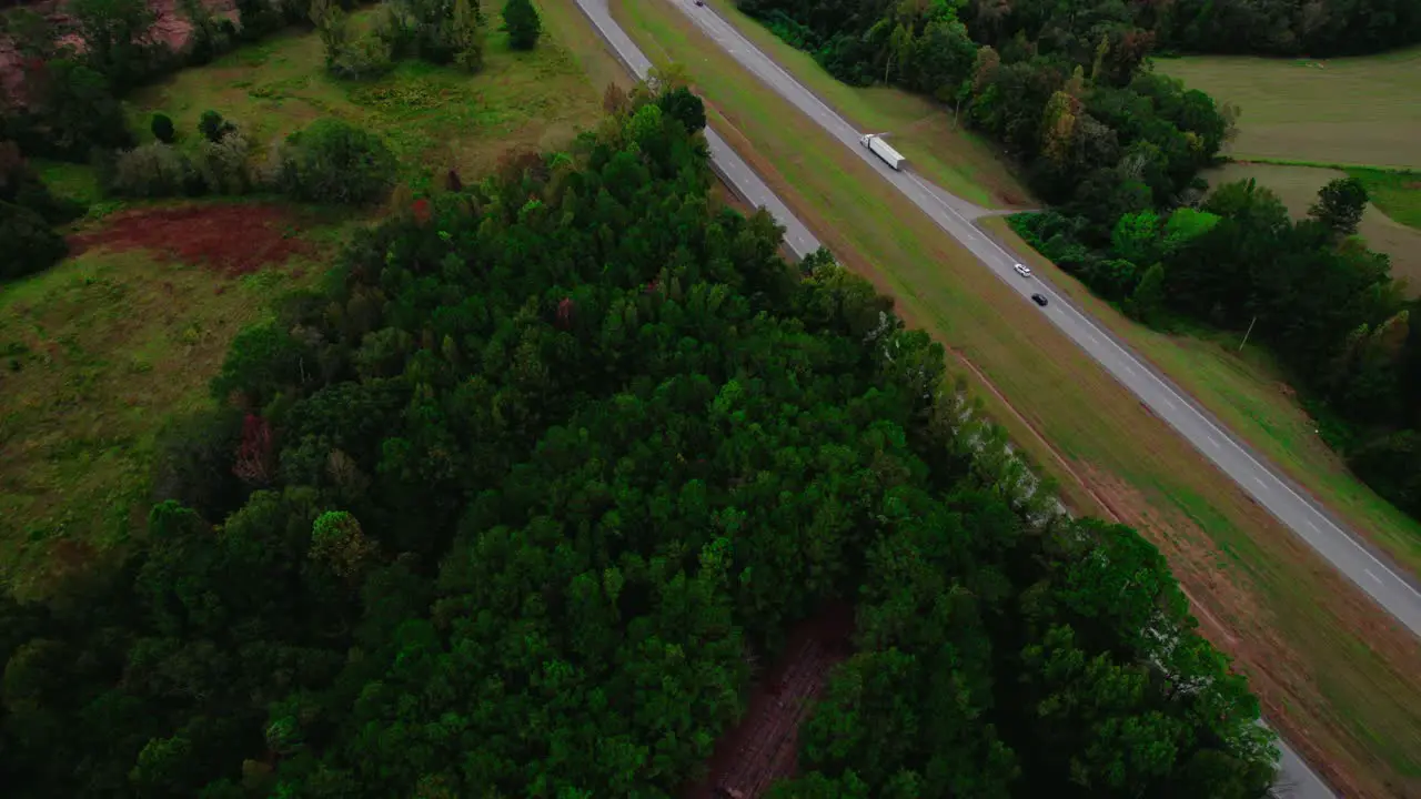 Semi-truck on forest-lined road aerial view captures the essence of rural transport