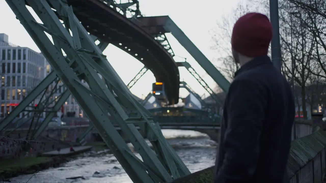 A man observing Wuppertal's suspended Train pass by in Germany at Dusk