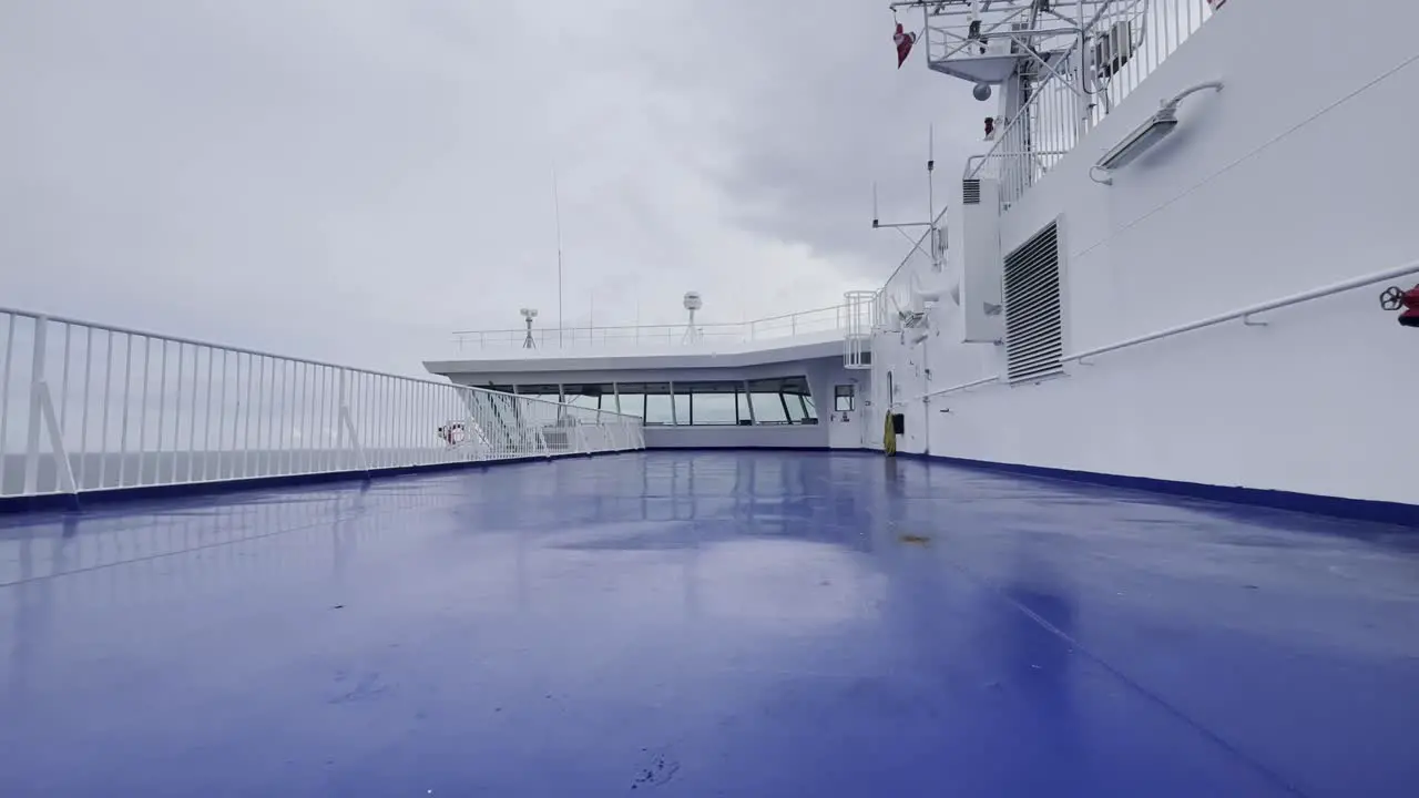 Covers a car ferry on the sea in light winds and a cloudy sky with the captain's steering bridge