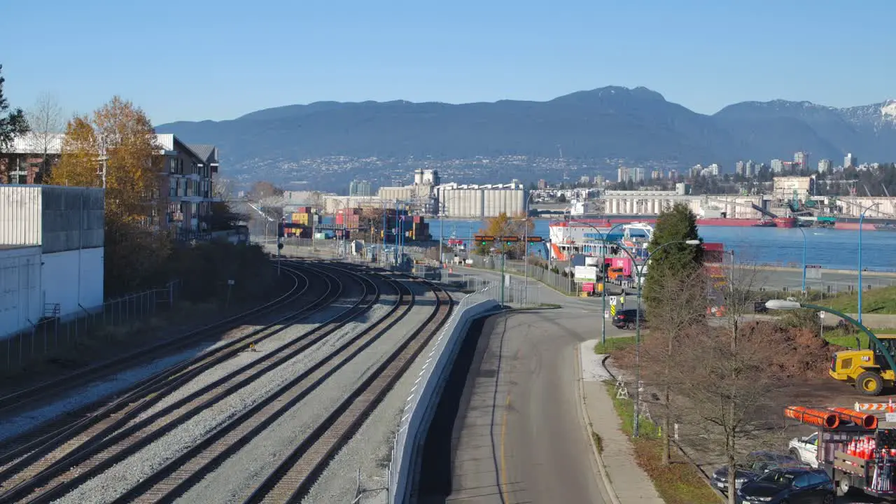 Railway tracks leading into an industrial port in Vancouver clear blue sky mountains in the background daytime