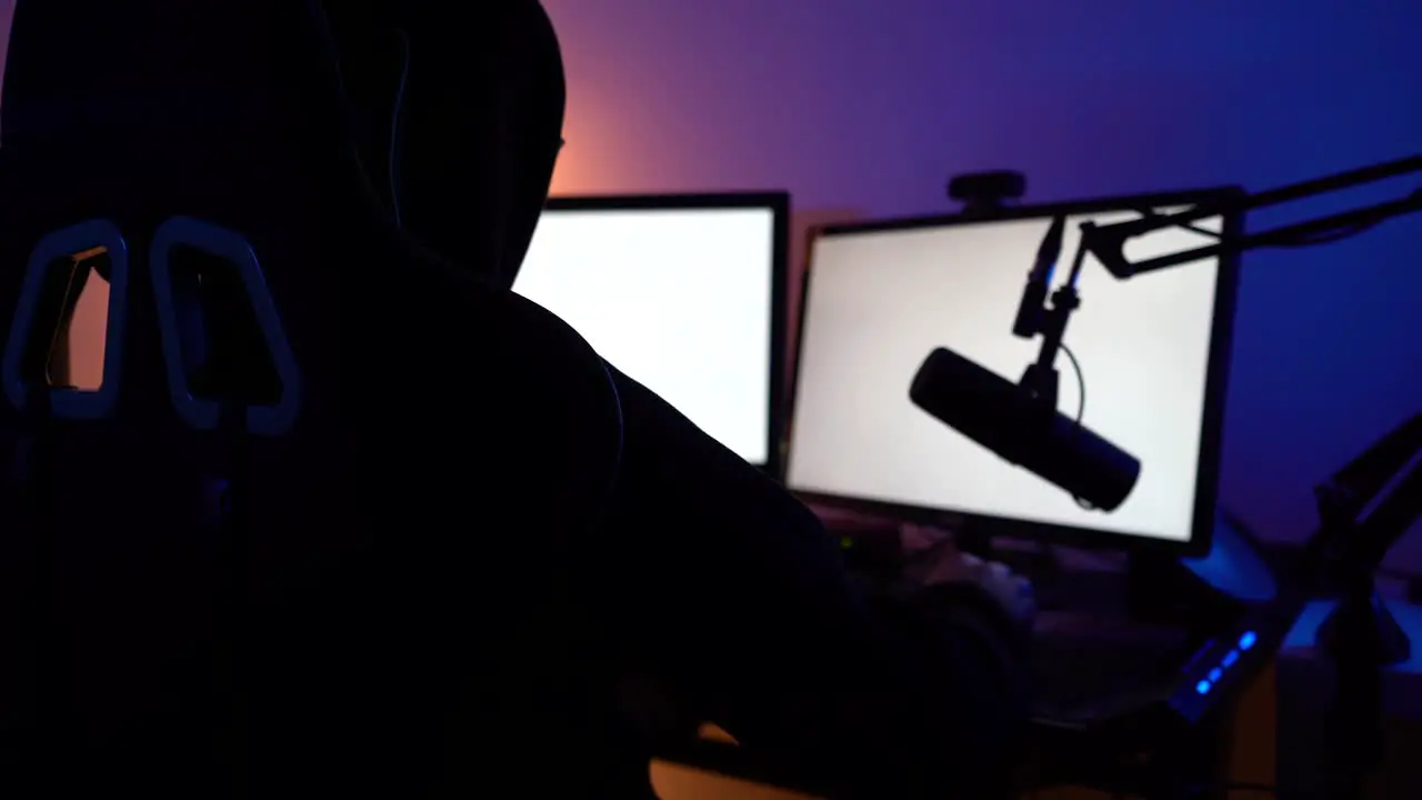 Dark hooded guy on blank monitor screen with microphone close