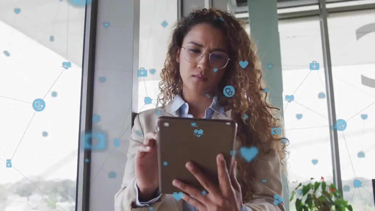 A biracial businesswoman sitting at a desk and using a tablet in modern office interiors