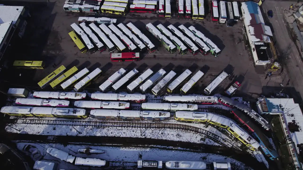 Aerial view of public transportations parking lot with buses and trams covered with snow