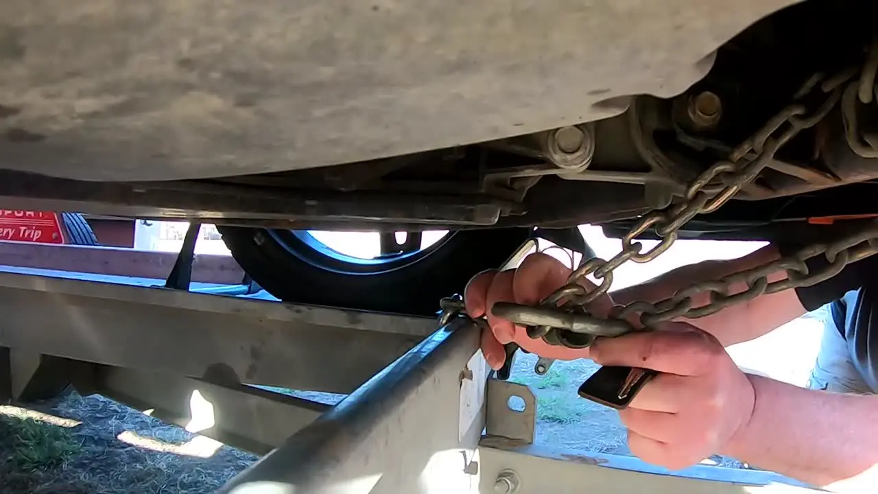 Taking the chains off the bottom of a car after transportation on a trailer