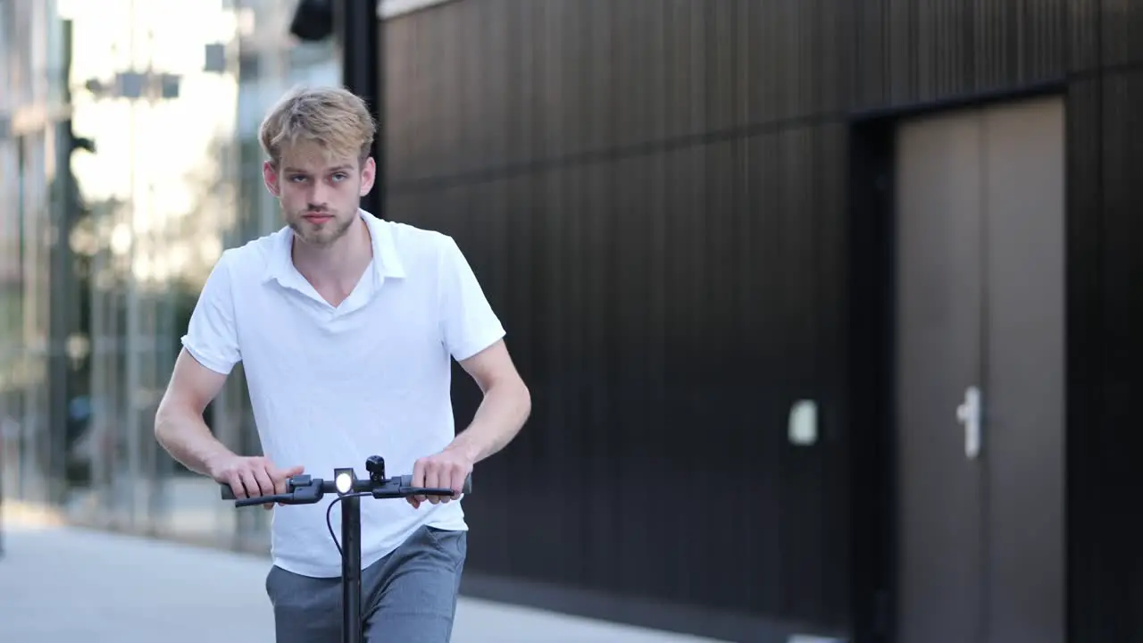 A young businessman gets on his e-scooter and drives away medium shoot