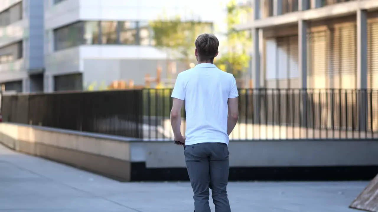 A young businessman rides his e-scooter past modern buildings