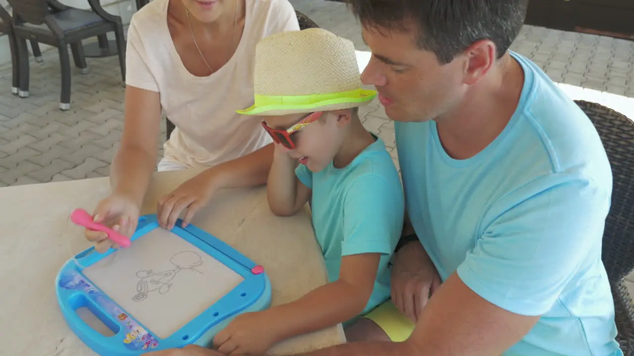 Father and son watch mother is painting pet on magnet board