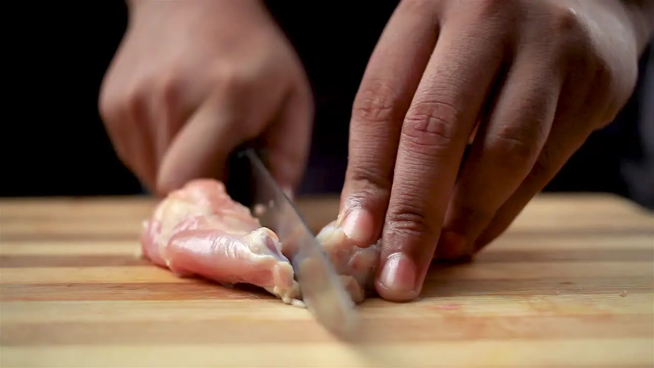 Butcher men cutting raw chicken wings with a sharp knife and shaping into a lollipop on a chopping board