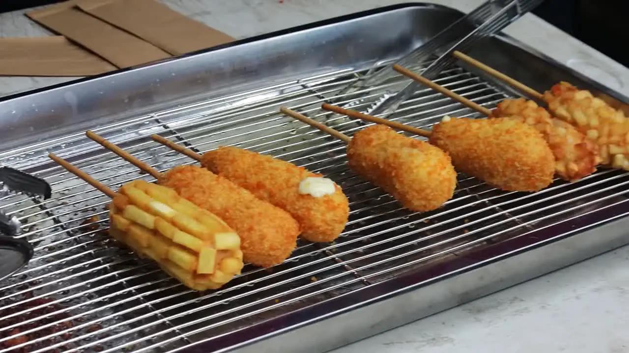 Close up shot of corn dog fried food being sold in a window during car free day carnival or fair