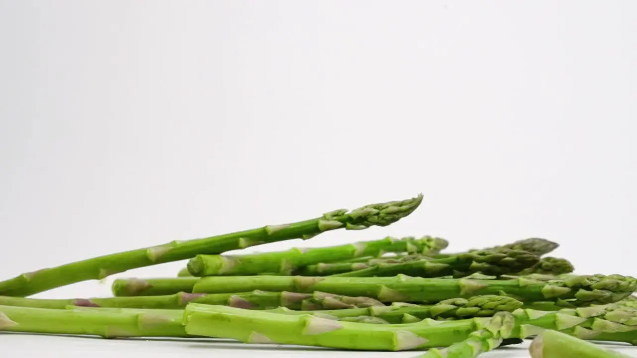 Asparagus stalks bouncing on white backdrop in slow motion