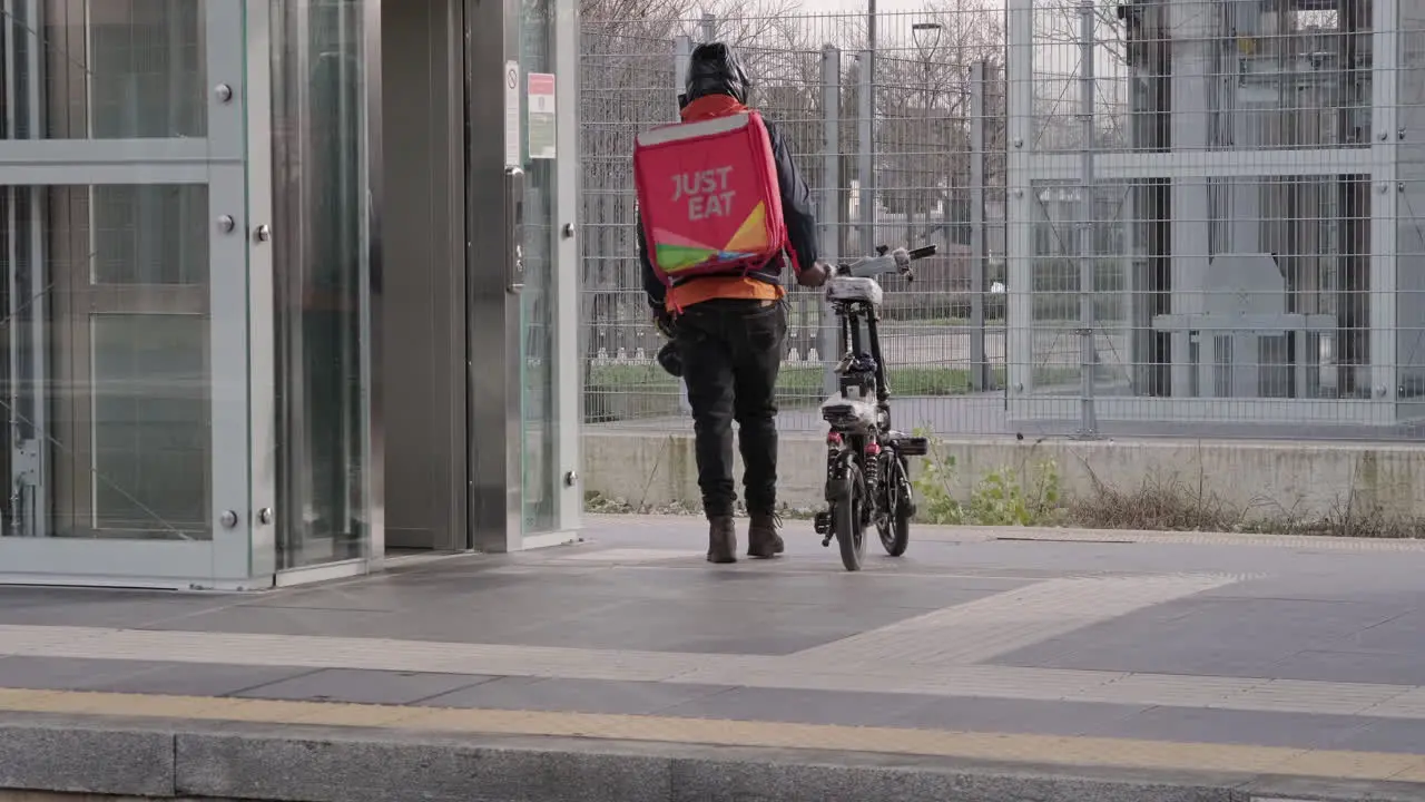 Food Raider Looks at Camera and Goes to Wait a Train on the Platform at the Station