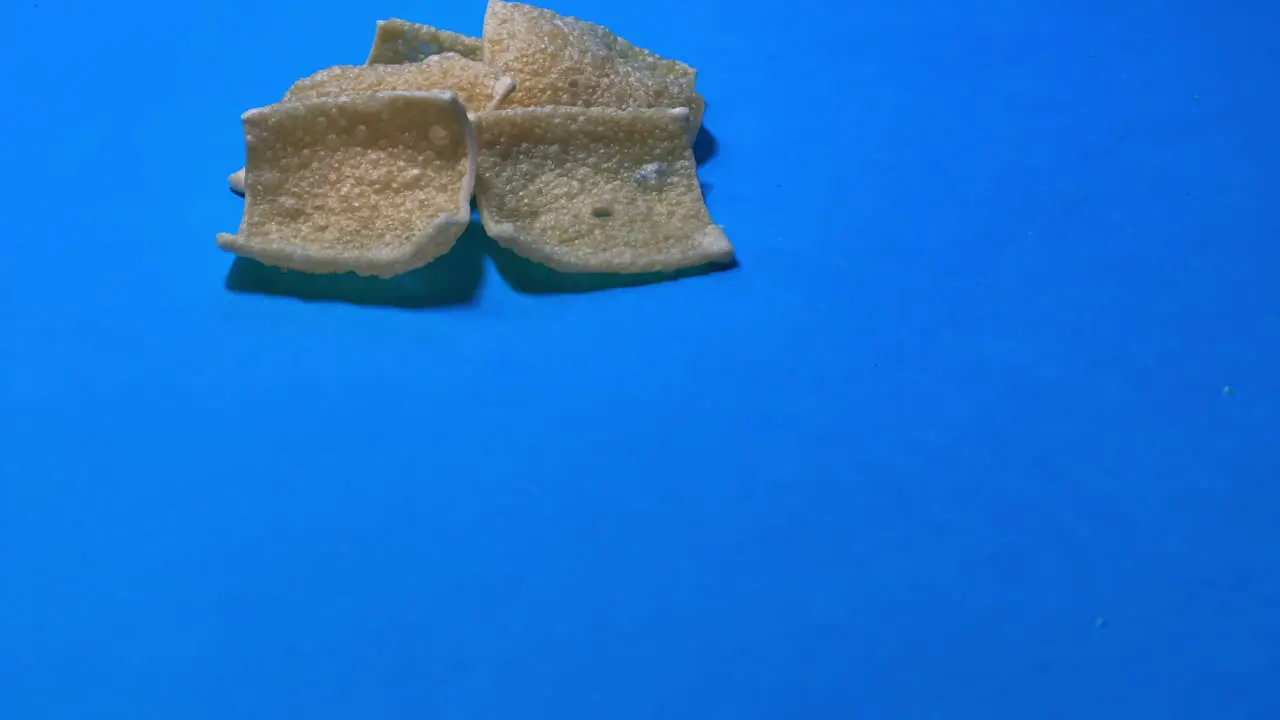 Close Up Of Tortilla Chips Rolling On Blue Surface