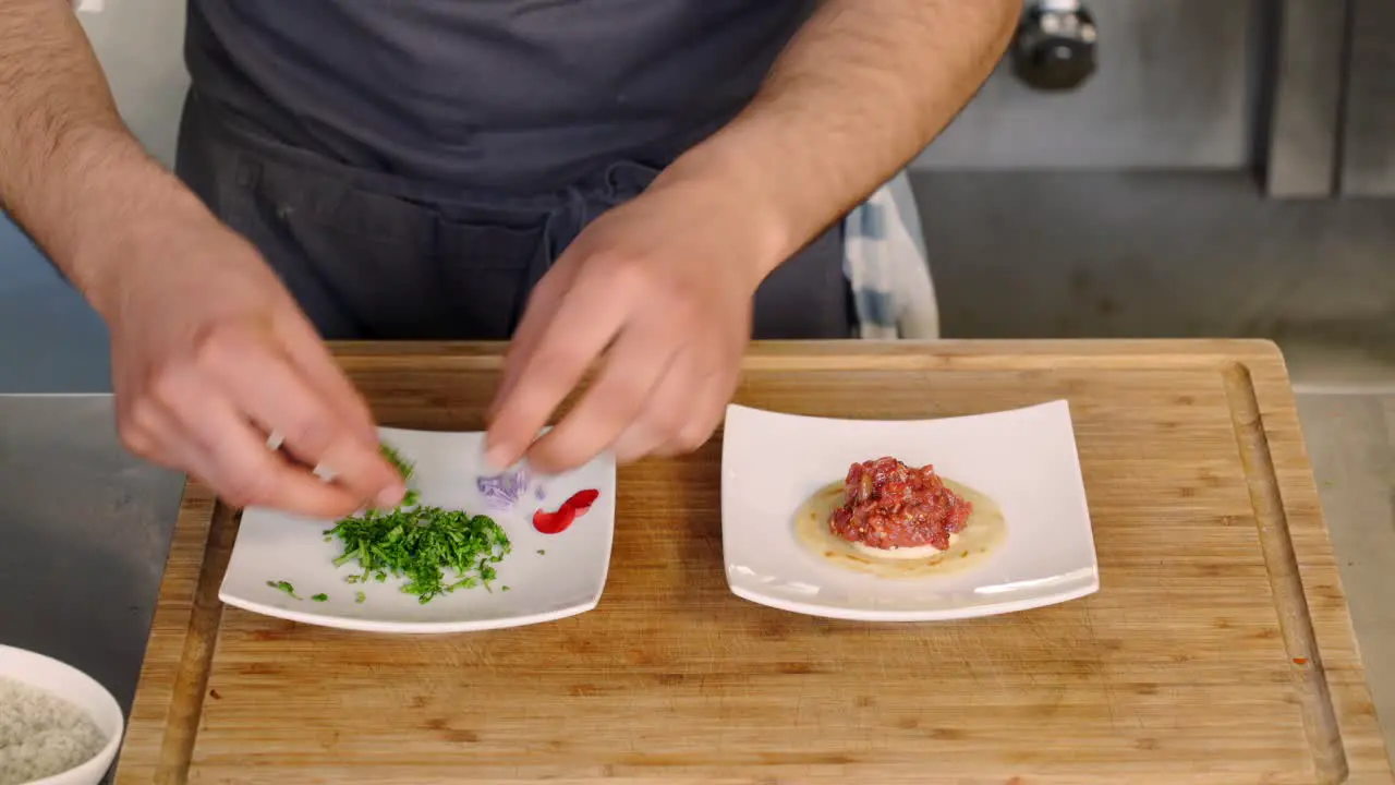 A chef adds garnish to an appetizer on a plate