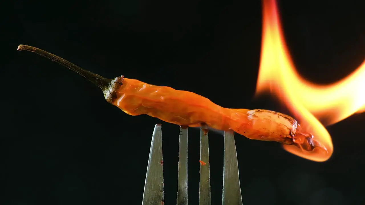 A fork with a fresh chili pepper on it is flambéed